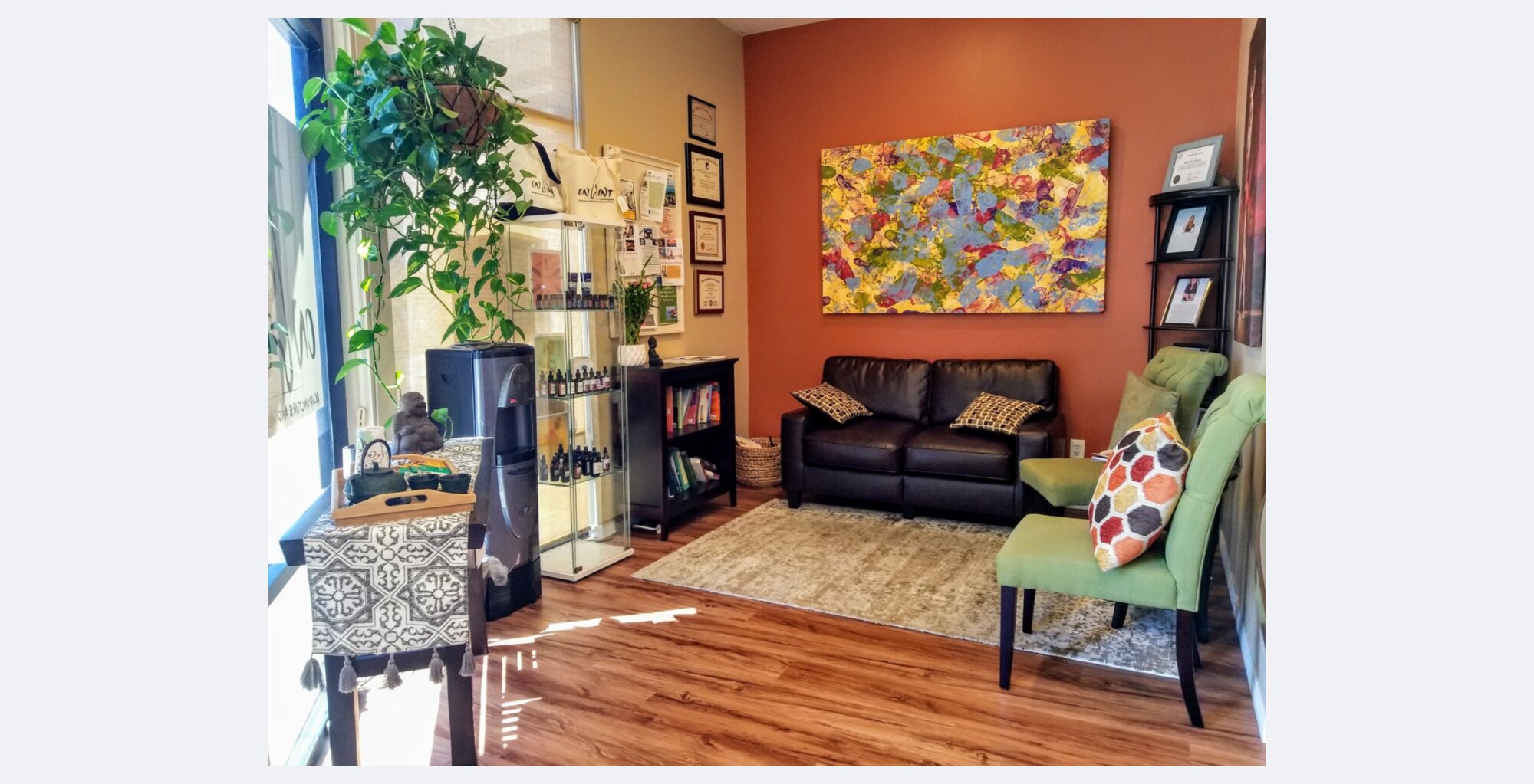 On Point relaxation room with leather sofa, green accent chair and an abstract canvas on a warm terracotta wall